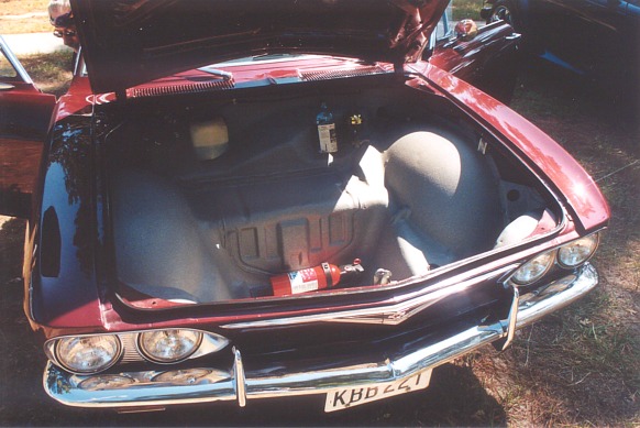 Red car trunk open showing spare tire and fire extinguisher. License plate KBD 221