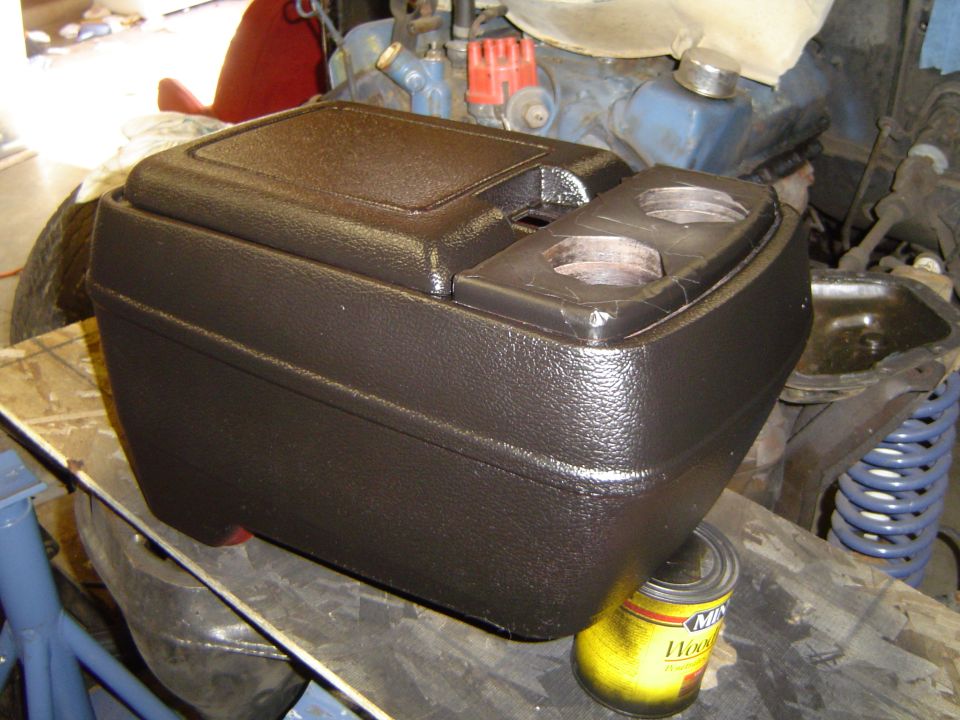 Brown center console with cup holders on a workbench