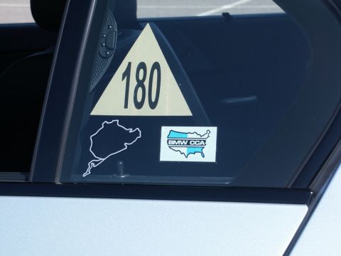 2001 Mercury Grand Marquis - A car window displays racing stickers, including a number, track outline, and club logo.