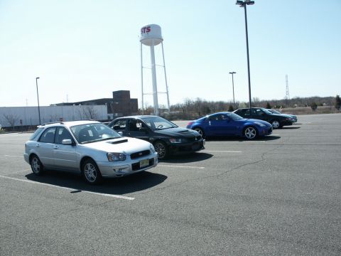 2001 Mercury Grand Marquis - Several cars parked in a lot under a water tower on a sunny day.