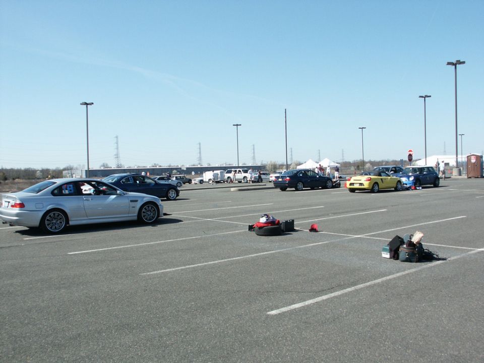 Silver BMW M3 coupe parked in lot, other cars and tents in background