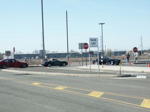 2001 Mercury Grand Marquis - Autocross event with multiple cars and cones. Signs direct participants and indicate parking areas.
