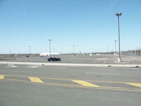 2001 Mercury Grand Marquis - A black convertible is navigating a course marked by orange cones in a large parking lot under a clear blue sky.