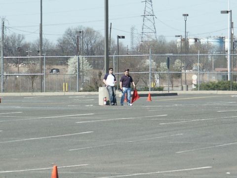 2001 Mercury Grand Marquis - Two men stand in a paved lot with orange cones and a fire extinguisher near a fence.