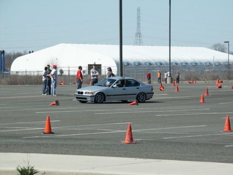 2001 Mercury Grand Marquis - A silver sedan drives through an autocross course with cones set up in a large parking lot.