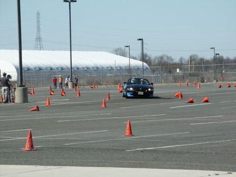 2001 Mercury Grand Marquis - A black convertible sports car drives through an autocross course marked by orange cones.