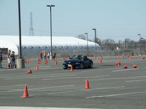 2001 Mercury Grand Marquis - A black convertible sports car maneuvers through an autocross course marked by orange cones on a sunny day.