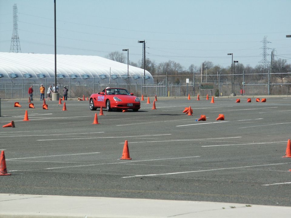Red convertible sports car navigating a cone course in a parking lot