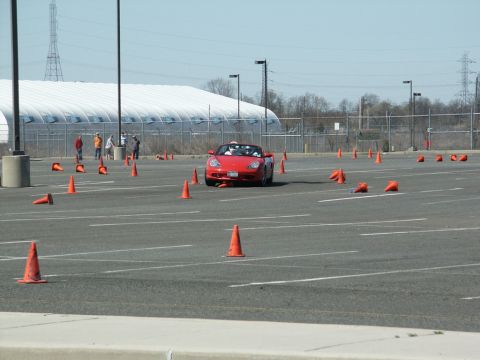 2001 Mercury Grand Marquis - A red convertible navigates an autocross course marked by orange cones in a large parking lot.