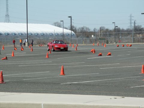 2001 Mercury Grand Marquis - A red convertible navigates an autocross course in a large parking lot.
