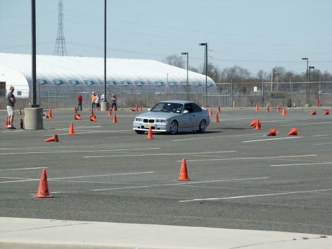 2001 Mercury Grand Marquis - A silver BMW E36 coupe is seen maneuvering through an autocross course marked by orange cones.
