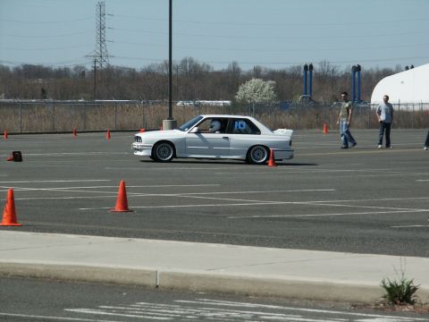 2001 Mercury Grand Marquis - A white BMW E30 coupe navigates an autocross course, marked with the number 10 on its door.
