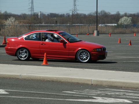 2001 Mercury Grand Marquis - A red BMW coupe navigates a course marked by orange cones during a track event.
