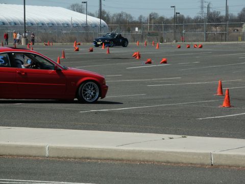 2001 Mercury Grand Marquis - A red car navigates a course marked by orange cones in an open lot.