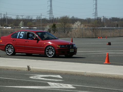 2001 Mercury Grand Marquis - Red BMW E46 sedan with racing number 15 participates in an event on a paved course.