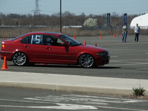 2001 Mercury Grand Marquis - A red BMW sedan navigates a course marked by orange cones, with two spectators in the background.
