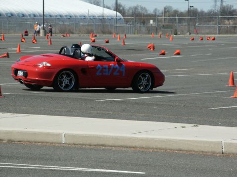 2001 Mercury Grand Marquis - A red convertible sports car navigates a course marked by orange cones on a sunny day.