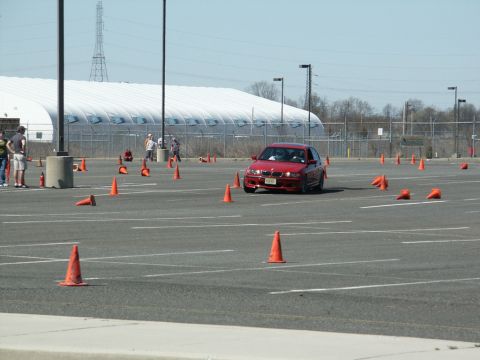 2001 Mercury Grand Marquis - A red BMW sedan navigates an autocross course marked by orange cones on a sunny day.