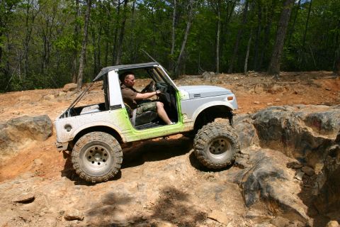 1990 Suzuki Samurai - Driver maneuvers a Suzuki Samurai over large rocks during an off-road excursion.