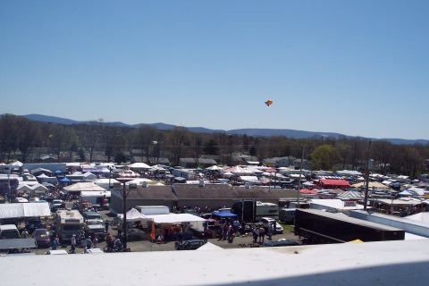 2001 Ford Crown Victoria - A wide view of a bustling outdoor market with numerous stalls and vehicles, set against a backdrop of hills.