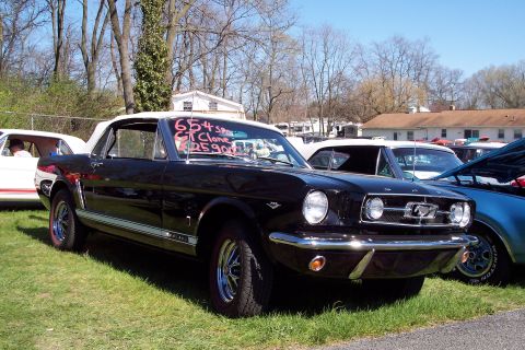 2001 Ford Crown Victoria - Black 1965 Ford Mustang convertible parked at an outdoor car show with other vehicles.