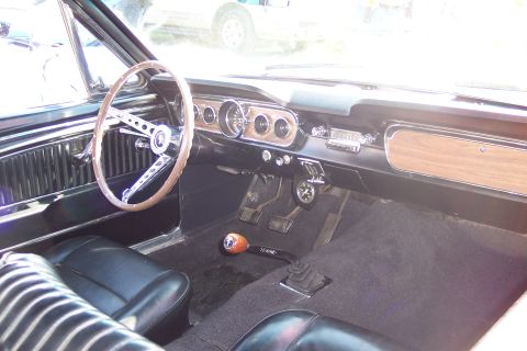 2001 Ford Crown Victoria - The interior of a vintage car features a wood-grain dash panel, a classic steering wheel, and black upholstery.