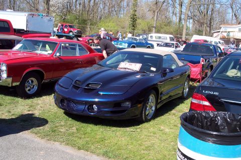2001 Ford Crown Victoria - A dark blue convertible sports car is parked on grass at an outdoor car show with other vehicles visible.