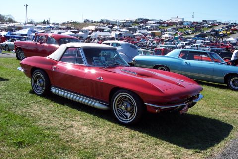2001 Ford Crown Victoria - Red convertible sports car at an outdoor car show with many other vehicles and tents.