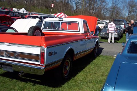 2001 Ford Crown Victoria - A two-tone GMC pickup truck is displayed at an outdoor car show with other vehicles and tents in the background.