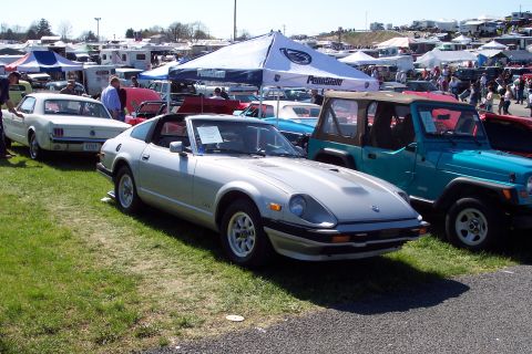 2001 Ford Crown Victoria - A silver Datsun 280ZX is parked on grass at an outdoor car show next to a teal Jeep.