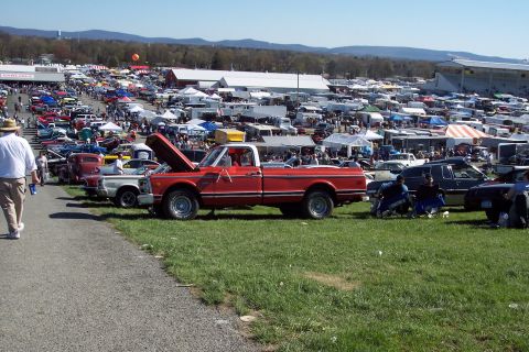 2001 Ford Crown Victoria - A red pickup truck is displayed with its hood open at a large outdoor car show event.
