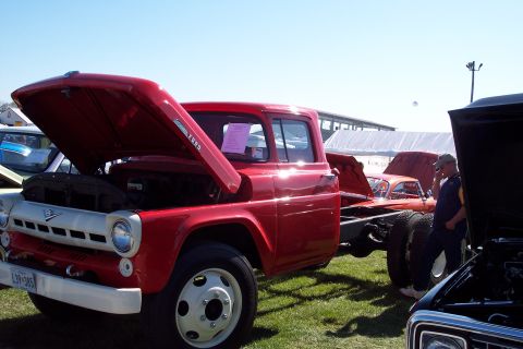 2001 Ford Crown Victoria - A red 1957 Ford truck is displayed with its hood open, alongside other vehicles at an outdoor event.