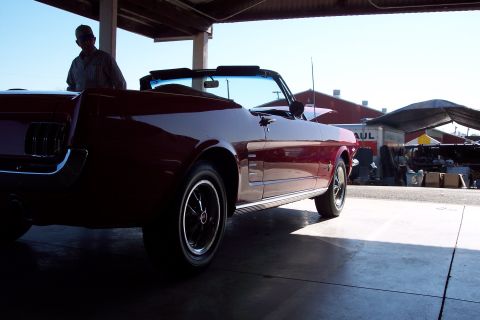 2001 Ford Crown Victoria - A red 1965 Ford Mustang convertible is parked under a covered area.