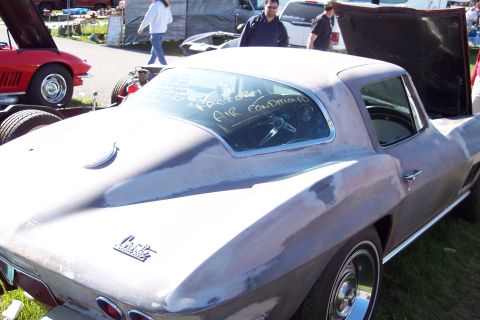 2001 Ford Crown Victoria - A 1963 Chevrolet Corvette Sting Ray coupe, possibly undergoing restoration, is seen at an outdoor event with text on its rear window.