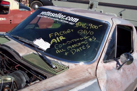 2001 Ford Crown Victoria - A vintage Corvette is displayed with sales information written on its windshield, with another vehicle visible behind it.