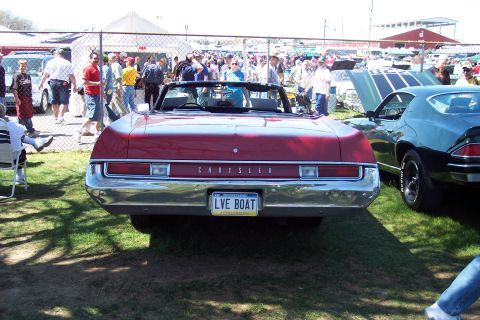 2001 Ford Crown Victoria - A red convertible with a Chrysler badge and a personalized license plate is parked on grass at an outdoor event.