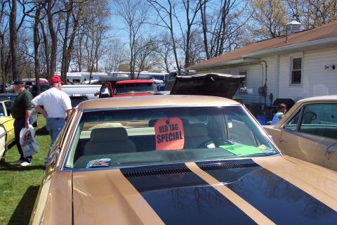 2001 Ford Crown Victoria - A gold car with racing stripes is parked outdoors with a red tag on its windshield.