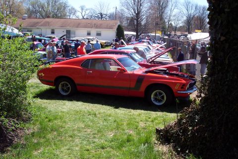 2001 Ford Crown Victoria - A red 1970 Ford Mustang Boss 302 is displayed at an outdoor car show with other vehicles.