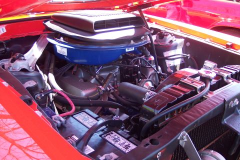 2001 Ford Crown Victoria - Close-up view of a red car's engine bay, showing the air cleaner, radiator, and battery.