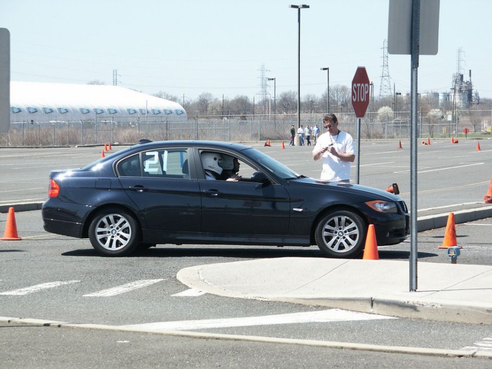 Dark sedan with number 21 on the window, driver wearing a helmet, at an autocross event