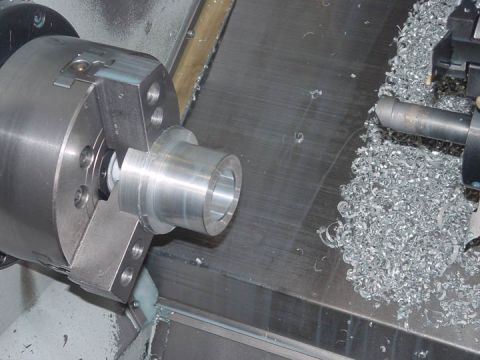 1979 Ford Bronco - A metal part is being machined on a lathe, with a pile of metal shavings accumulating on the machine bed.