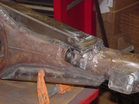1979 Ford Bronco - Metal axle housing with extensive welding, secured by clamps for work.