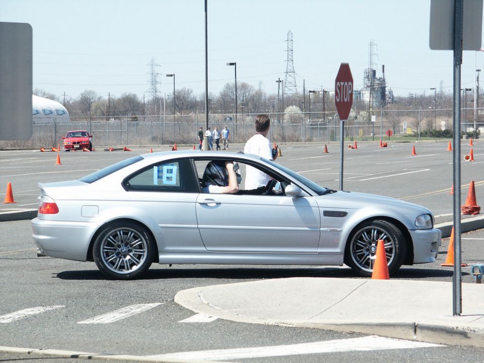 Silver BMW M3 E46 coupe with racing number 18 on door, driving on a course with orange cones