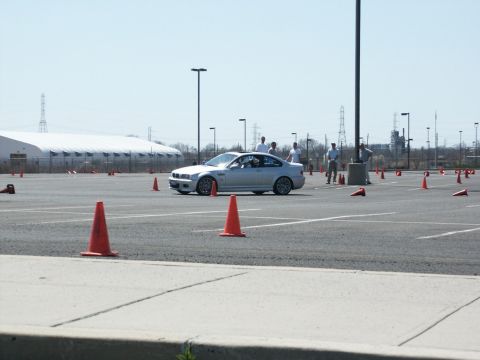 2001 Mercury Grand Marquis - A silver BMW M3 coupe is seen on an autocross course, maneuvering around orange cones on a sunny day.