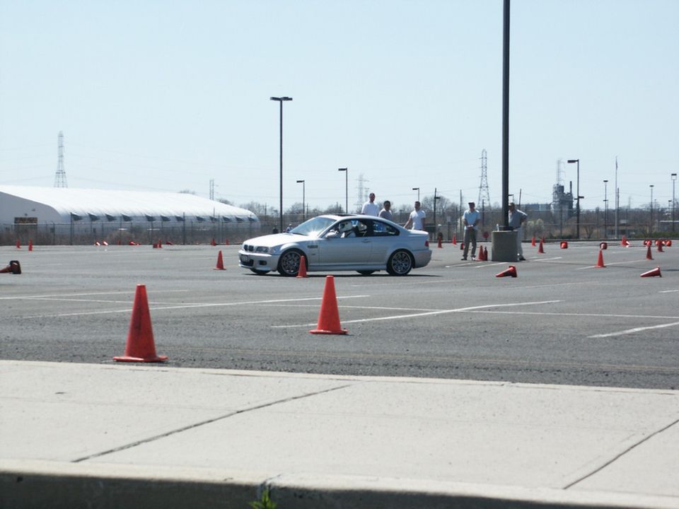 Silver BMW M3 coupe navigating an autocross course with orange cones