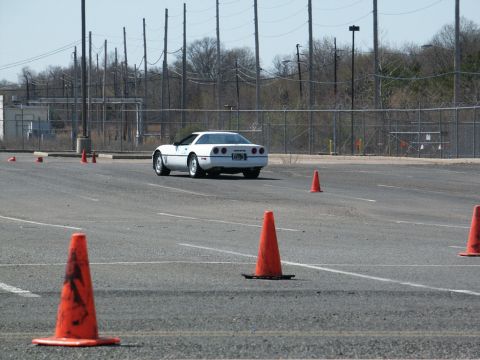 2001 Mercury Grand Marquis - A white Chevrolet Corvette navigates a course marked by orange traffic cones on a sunny day.