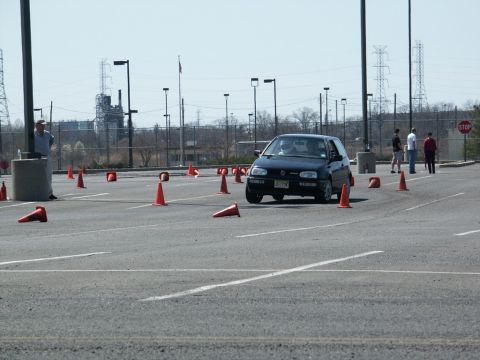 2001 Mercury Grand Marquis - A black hatchback navigates an autocross course marked by orange cones on a sunny day.