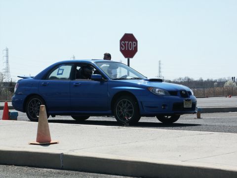 2001 Mercury Grand Marquis - A blue Subaru Impreza WRX is seen on a race track with orange cones and a stop sign in the background.