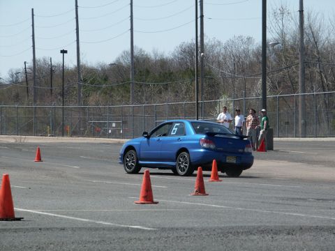 2001 Mercury Grand Marquis - A blue Subaru WRX STI participates in an autocross event, with cones marking the course.