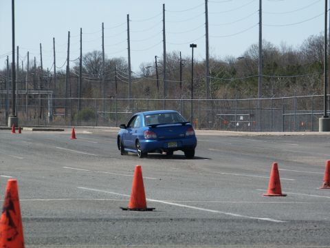 2001 Mercury Grand Marquis - A blue Subaru WRX navigates an autocross course marked by orange cones on a sunny day.